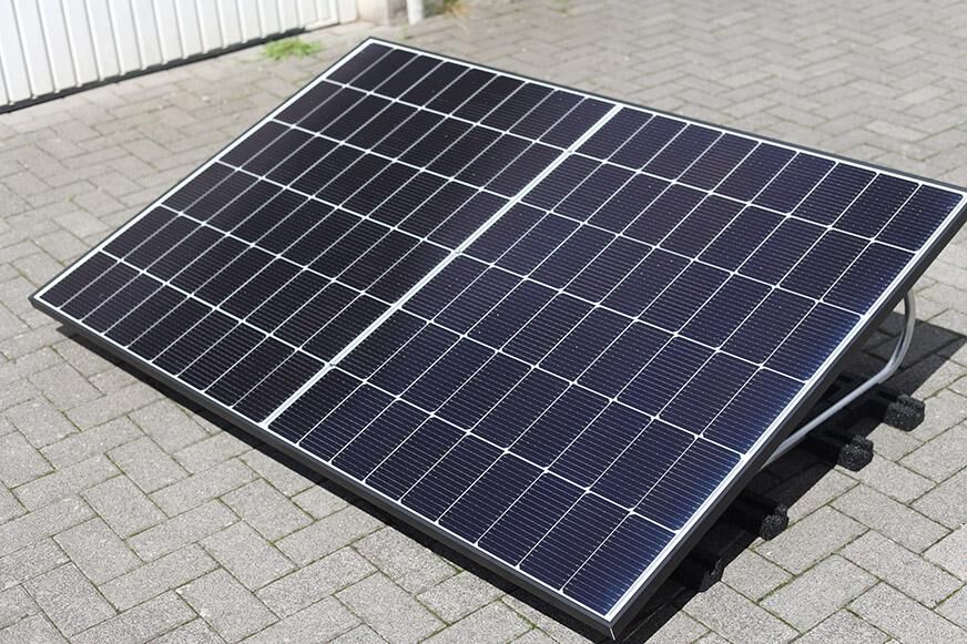 Ein Solarmodul steht in der Sonne auf einem flachen Gelände und ist angewinkelt.  
